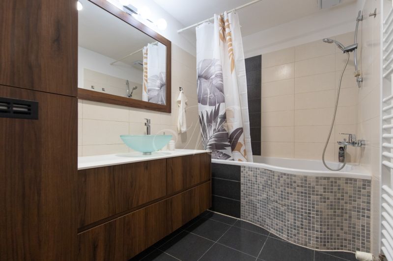 Bathroom in a 2-room apartment with a bathtub, sink, and tiled floor.
