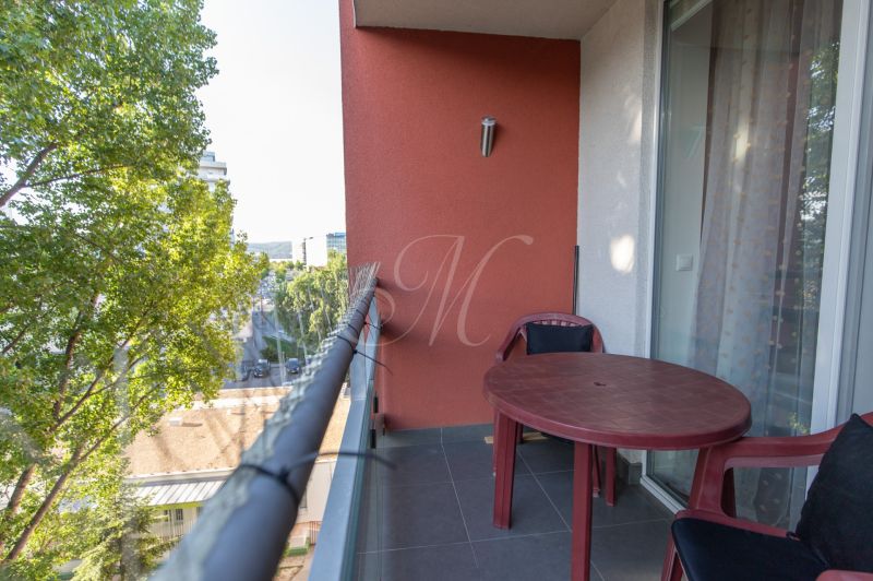 A balcony of a 2-room apartment with plastic furniture and a view of greenery.