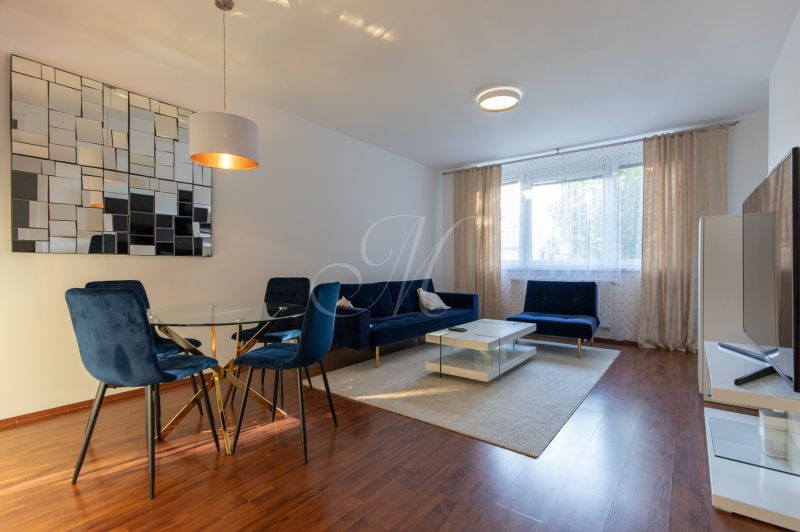 Living room in a two-room apartment with blue chairs and wood-patterned flooring.