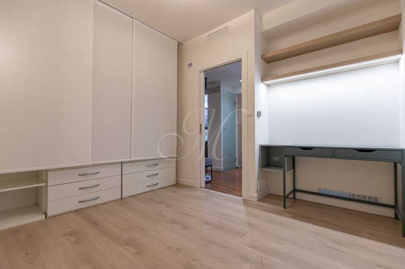 A bright room with a desk, a built-in wardrobe, and a wooden decor floor in a 2-room apartment.