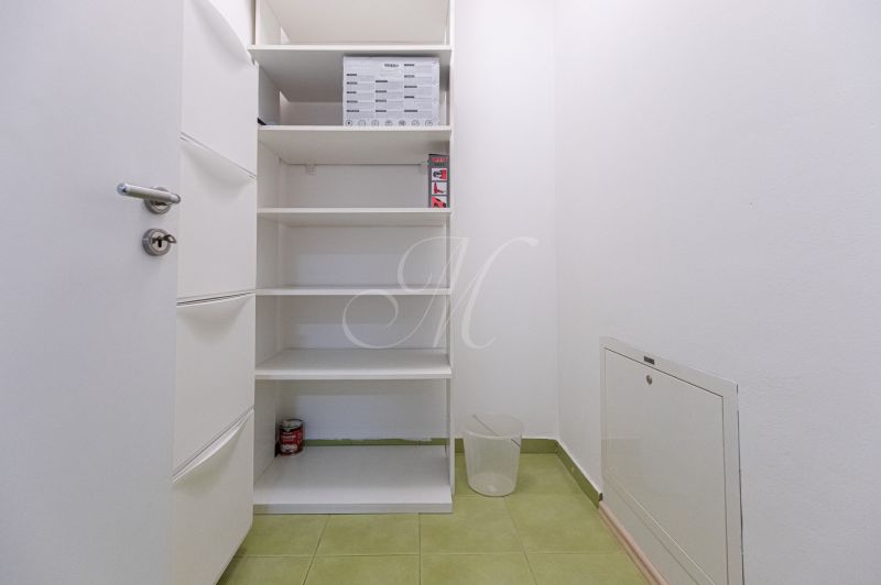 Storage space with shelves and green flooring in a 2-room apartment.