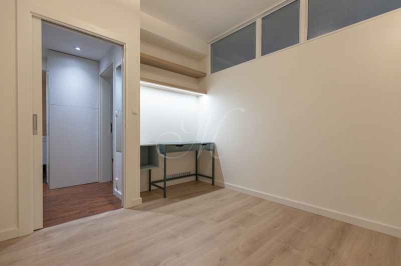 Empty room with wood-patterned flooring and a built-in desk in a two-room apartment.