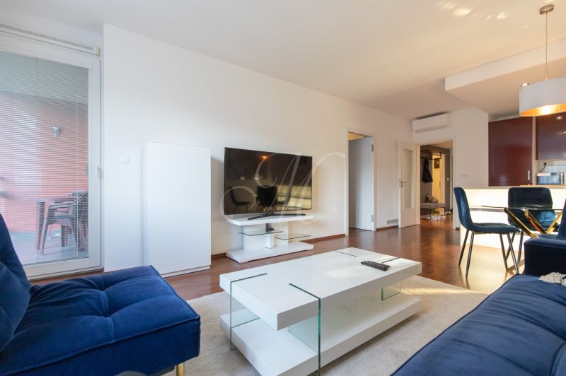 Living room in a two-room apartment with a wooden decor floor and balcony doors.