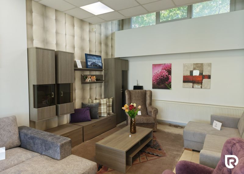 Commercial spaces with wood-patterned flooring, sofas, an armchair, and decorative cushions.