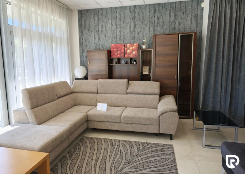 Commercial space with a beige sofa, wooden cabinet, and patterned carpet.