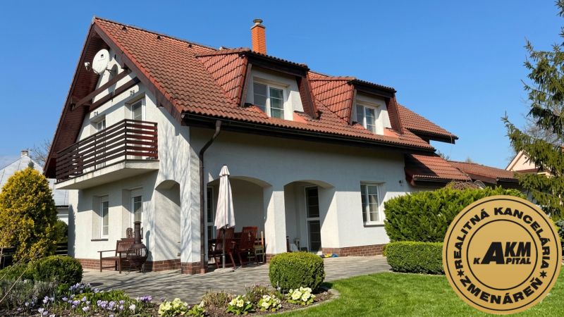 A family house in Sliač with a red roof, a balcony, and a garden with flowers.