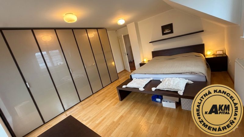 A bedroom in a family house with a wooden decor floor and a large wardrobe.