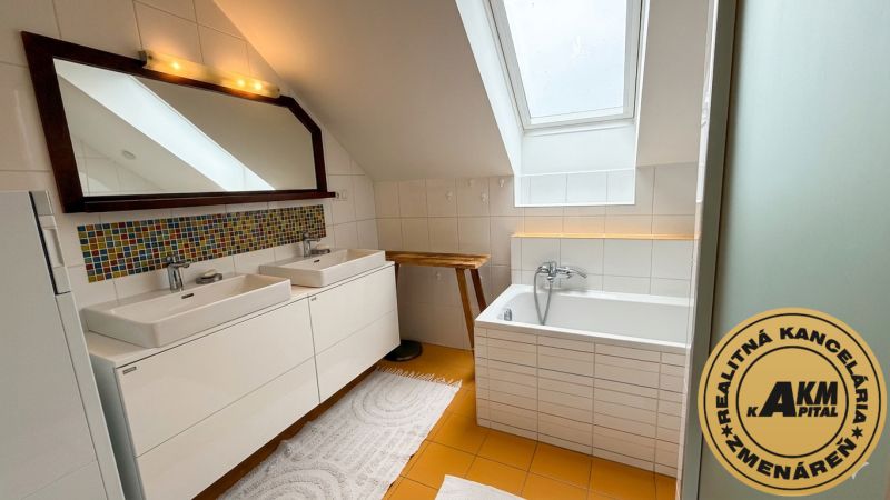 Bathroom with double sink, bathtub, and decorative tiles in a family house.