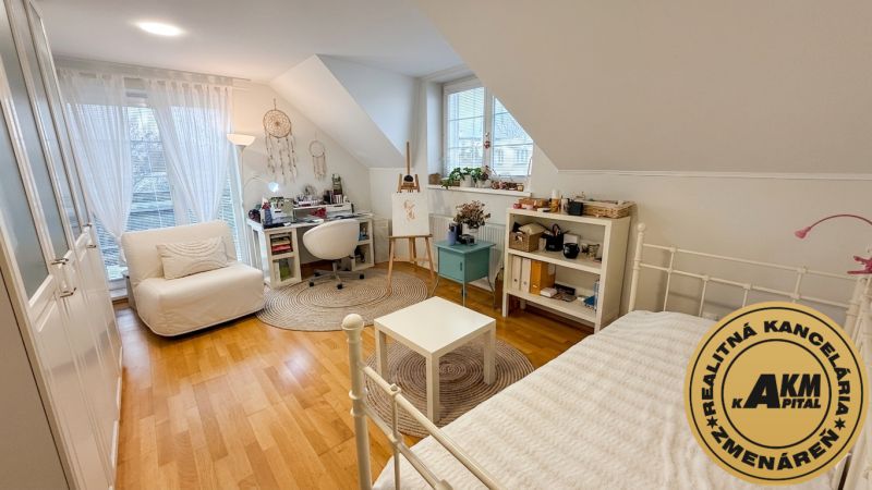 A bright bedroom in a family house with a wood-patterned floor and a writing desk.