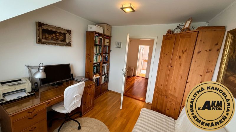 A home office in a family house with wooden decor and shelves full of books.