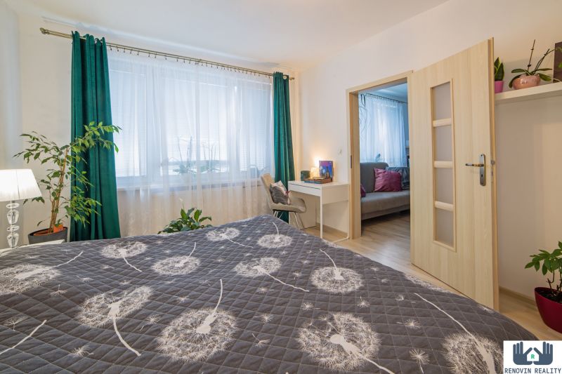 Bedroom with a dandelion-patterned bedspread, a writing desk, and a wooden decor floor.