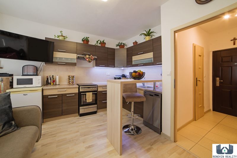 A kitchen in a studio apartment with a wooden decor floor and modern equipment.