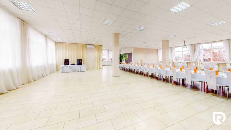 Commercial space with wood-patterned flooring, tables and chairs arranged in a row.