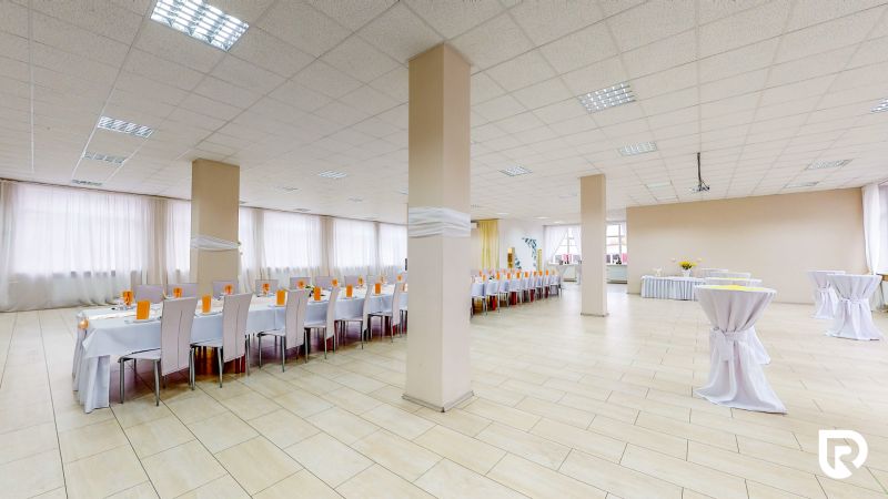 A large room with white tables and chairs, a floor with a wooden decor, and decorations.