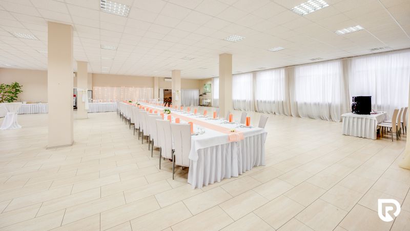 A large hall with decorated tables and a wooden-patterned floor for commercial purposes.