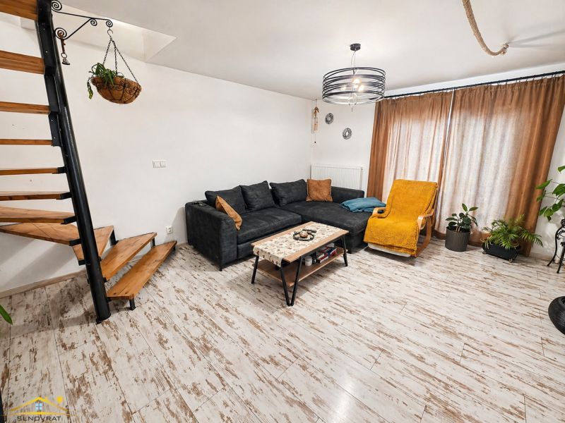 Living room in a family house with a wooden decor floor, a sofa, and stairs.