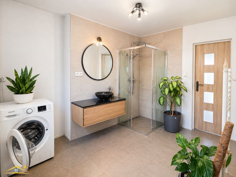 Spacious bathroom with a large shower, sink on a cabinet, and washing machine.