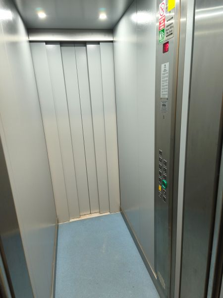 Modern elevator interior with steel walls and a simple control panel.