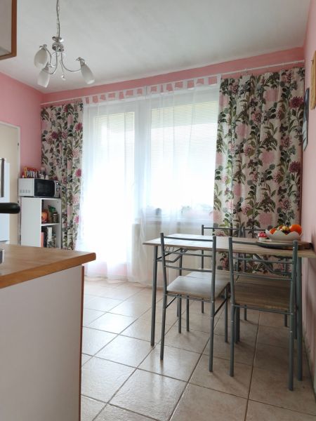 Dining area in a 2-room apartment with a table and floral curtains.