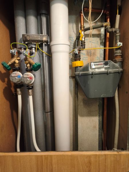 Plumbing and gas meter in a 2-room apartment with a wooden decor floor.