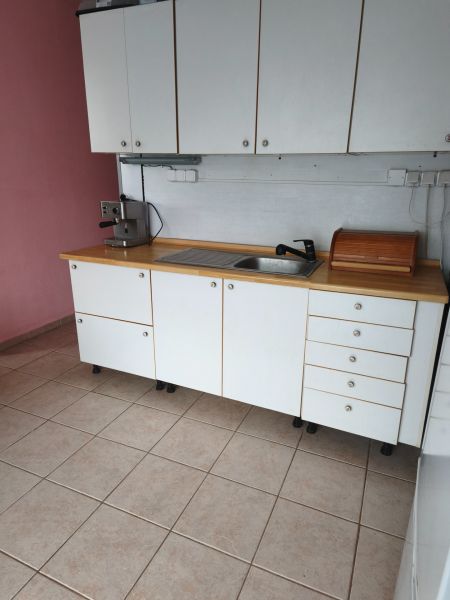 A kitchen in a 2-room apartment with white cabinets, tiles, and a coffee maker.