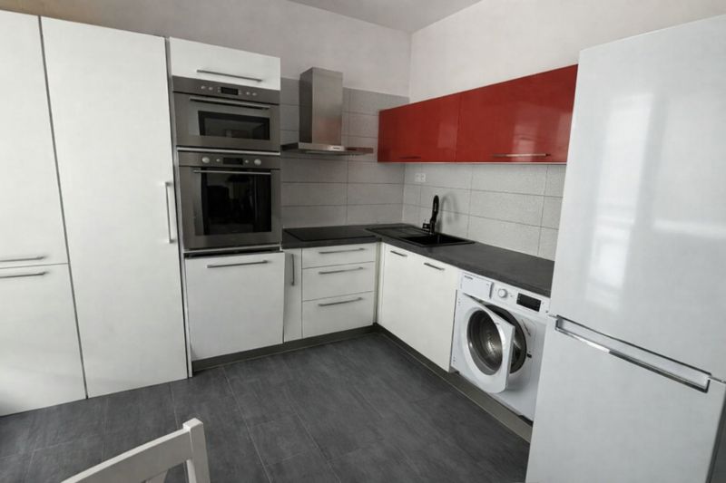 The kitchen of a 4-room apartment with an L-shaped kitchen unit, an oven, and a washing machine.