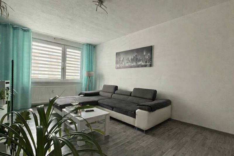 Living room in a 4-room apartment with a large sofa and a floor with a wooden decor.