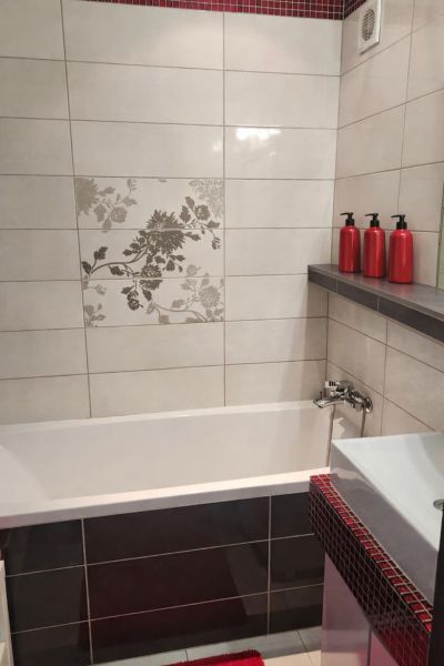A bathroom in a 4-room apartment with tiles and red accessories.