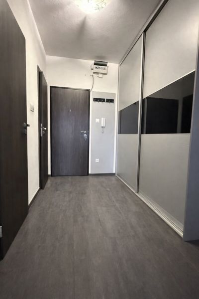 A hallway in a 4-room apartment with a built-in wardrobe and a floor with a wooden decor.
