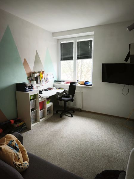 A workspace in a 4-room apartment with carpet flooring and geometric patterns on the wall.