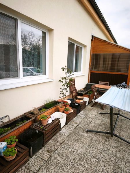 Terrace of a 4-room apartment in Malá Lehota with flower pots, plants, and garden furniture.