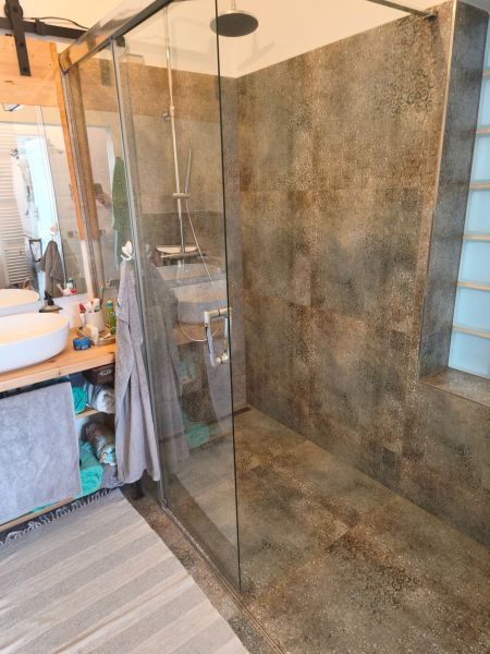 A bathroom in a 4-room apartment with a large shower and a glass screen.