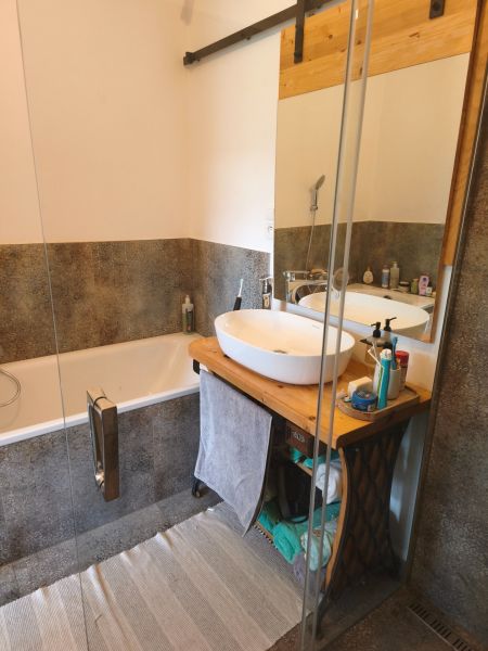 A bathroom with a wooden washbasin counter and a bathtub in a 4-room apartment.