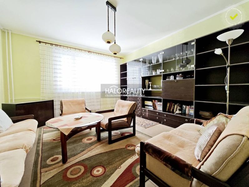 A bright living room in a two-room apartment with wooden furniture and a large bookshelf.
