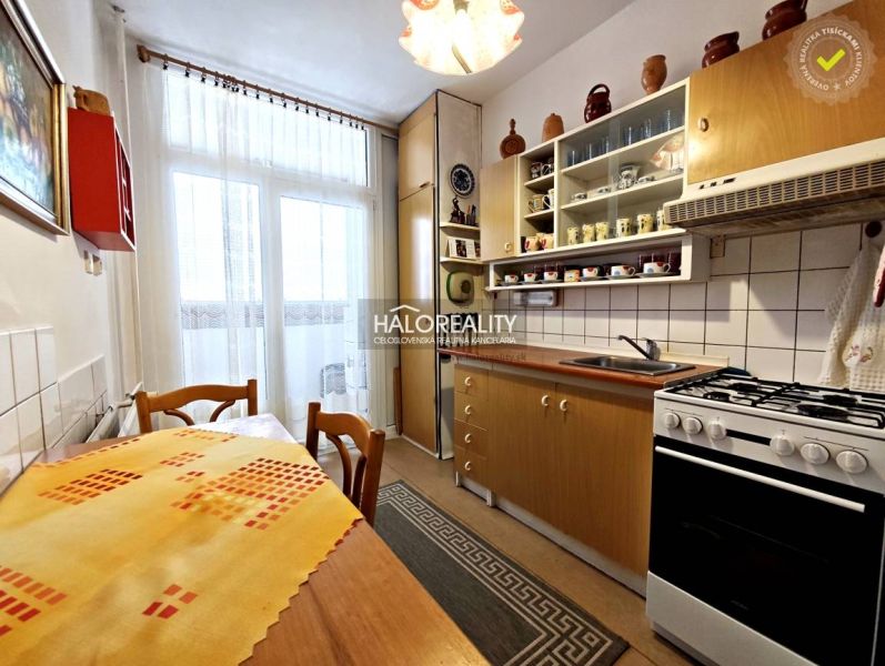 A kitchen in a 2-room apartment with a wooden decor floor and a balcony window.