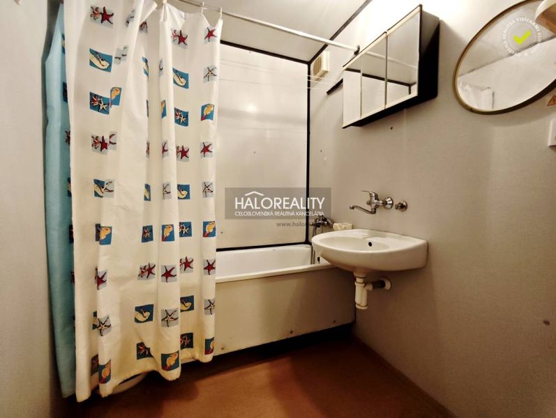 A bathroom in a 2-room apartment with a bathtub and a curtain, a sink with a mirror.