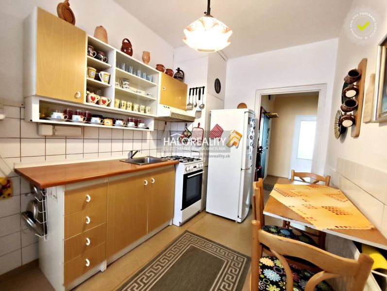 A kitchen in a 2-room apartment with wooden cabinets and a dining area.