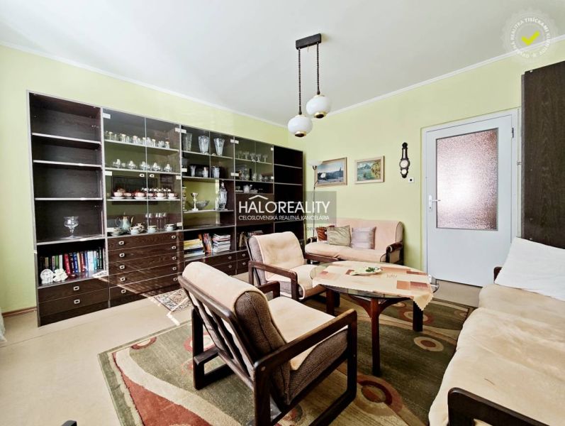 Living room in a two-room apartment with a sofa, armchairs, and a large bookshelf.