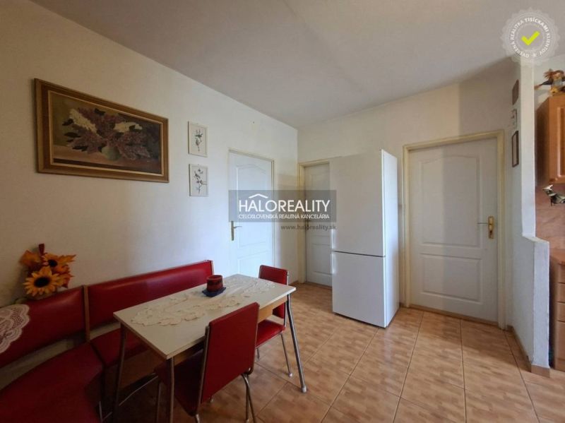A kitchen in a 3-room apartment with a white refrigerator, red seating, and decorations.