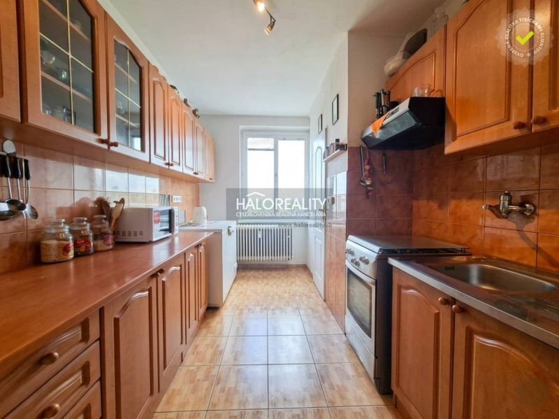 A kitchen in a 3-room apartment with wooden cabinets and a floor with a wood decor.