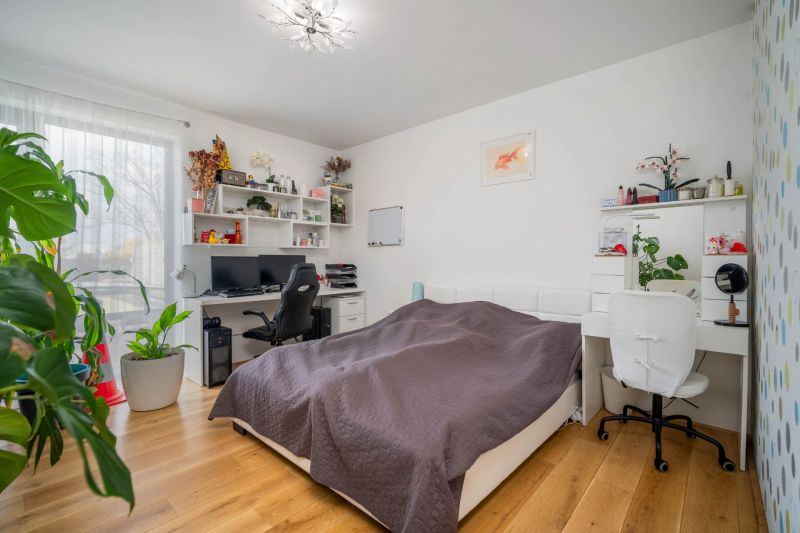 A bedroom in a family house with a desk, computer, and wooden decor flooring.