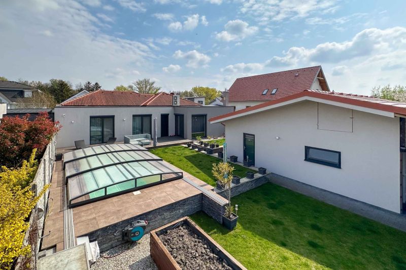 A family house in Pama with a landscaped garden, glass shelter, and lawn.