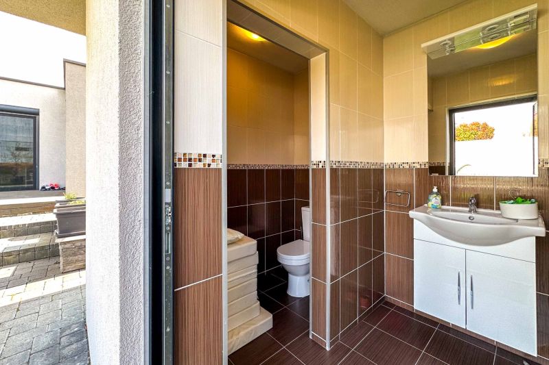A bathroom in a family house with a sink, toilet, and mosaic tiles.