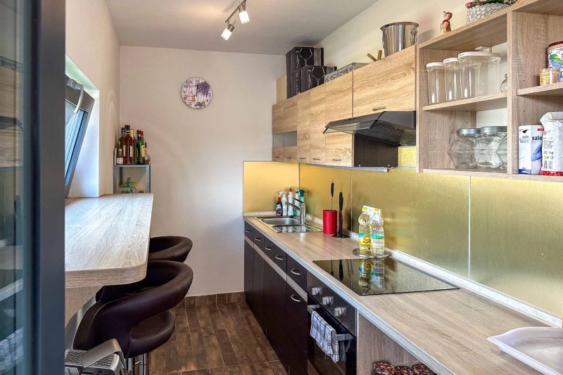 A kitchen with wooden decor, storage spaces, and a bar counter in a family house.