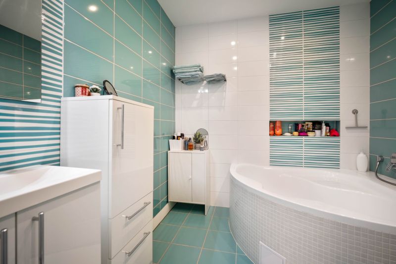 A bathroom in a family house with turquoise tiles and white furniture.