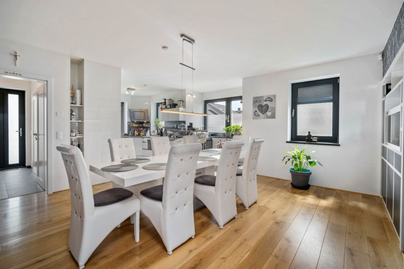 Dining room in a family house with a wooden decor floor, white chairs, and a houseplant.