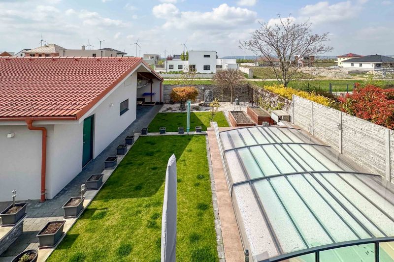 A family house in Pama with a landscaped yard, a swimming pool, and a garden lined with plants.