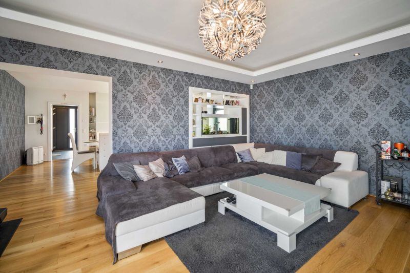 Living room in a family house with dark patterned wallpaper and a wooden decor floor.