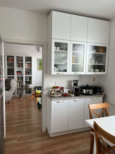A kitchen in a 3-room apartment with white cabinets and a wood-patterned floor.