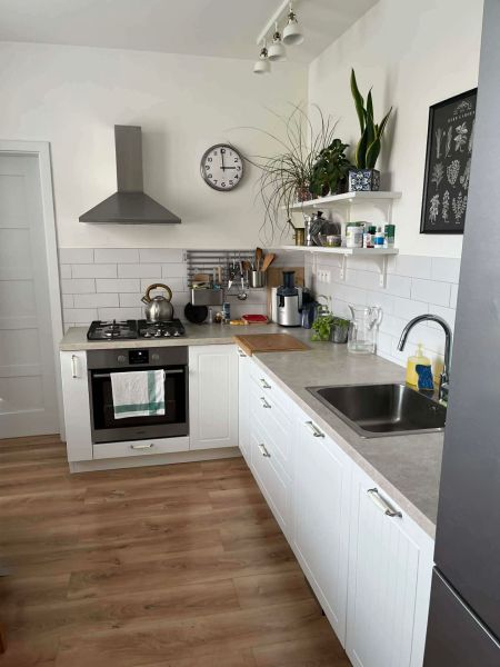 A kitchen in a 3-room apartment with white cabinets and a wooden decor floor.